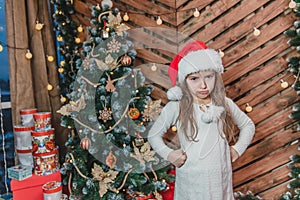 Disappointed little girl wearing Christmas costume standing isolated over wooden christmas background, keeping arms