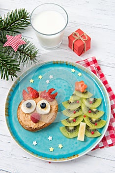 Christmas pancake in a shape of reindeer made of fresh fruits and berries and kiwi christmas tree. Healthy food for kids ideas.