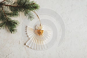 Christmas paper angel hanging on the tree branch on white textured background. Christmas holiday concept. Top view