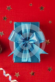 Christmas, party or birthday blue gift box or present with blue bow ribbon on red background