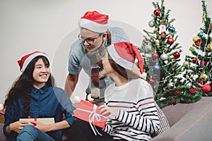 Christmas party with friends, asian people exchange gift and giving present with smiling face,Holiday xmas celebration concept.