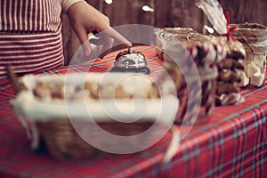 Christmas pastry shop. Woman seller, waitress ringing bell to warn that home made gingerbread cookies is ready. Selling marshmallo