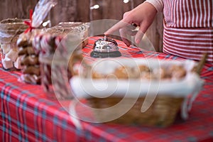 Christmas pastry shop. Woman seller, waitress ringing bell to warn that home made gingerbread cookies is ready. Selling marshmallo