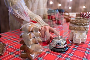 Christmas pastry shop. Woman seller, waitress ringing bell to warn that hot chocolate in paper cup is ready. Gingerbread cookies