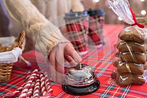 Christmas pastry shop. Woman seller, waitress ringing bell to warn that hot chocolate in paper cup is ready. Gingerbread cookies