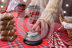 Christmas pastry shop. Woman seller, waitress ringing bell to warn that hot chocolate in paper cup is ready. Gingerbread cookies