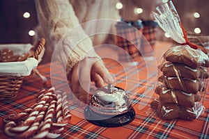 Christmas pastry shop. Woman seller, waitress ringing bell to warn that hot chocolate in paper cup is ready. Gingerbread cookies