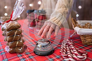 Christmas pastry shop. Woman seller, waitress ringing bell to warn that hot chocolate in paper cup is ready. Gingerbread cookies