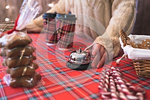 Christmas pastry shop. Woman seller, waitress ringing bell to warn that hot chocolate in paper cup is ready. Gingerbread cookies