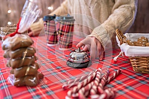 Christmas pastry shop. Woman seller, waitress ringing bell to warn that hot chocolate in paper cup is ready. Gingerbread cookies