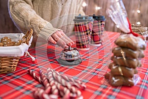 Christmas pastry shop. Woman seller, waitress ringing bell to warn that hot chocolate in paper cup is ready. Gingerbread cookies