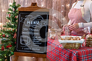 Christmas pastry shop . Woman seller, waitress selling gingerbread, marshmallows, cookies, sweets and hot chocolate