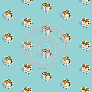 Christmas pattern made with New Year gifts with golden bows on bright light blue background. Minimal Christmas concept.