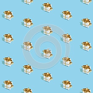 Christmas pattern made with New Year gifts with golden bows on bright light blue background. Minimal Christmas concept.