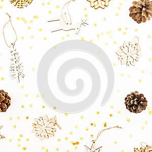 Christmas pattern with wooden tree decoration, snowflakes and pine cones on white. Flat lay, top view. Winter festive frame