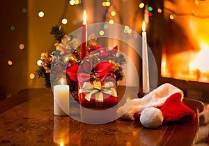 christmas photo of burning candles with giftbox against fireplace