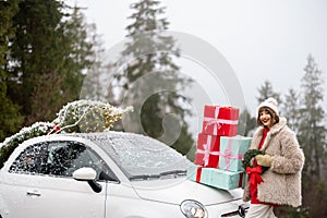 Christmas photo card of a woman with presents and car in mountains on snowy weather