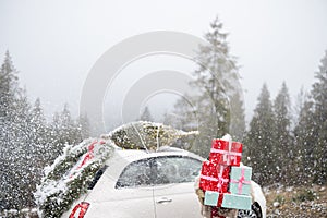 Christmas photo card of a woman with presents and car in mountains on snowy weather