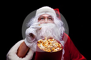 Christmas. Photo of Santa Claus gloved hand With a red bucket with popcorn, on a black background