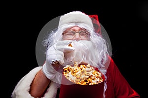 Christmas. Photo of Santa Claus gloved hand With a red bucket with popcorn, on a black background