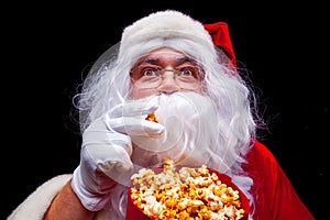 Christmas. Photo of Santa Claus gloved hand With a red bucket with popcorn, on a black background