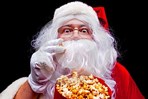 Christmas. Photo of Santa Claus gloved hand With a red bucket with popcorn, on a black background