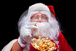 Christmas. Photo of Santa Claus gloved hand With a red bucket with popcorn, on a black background