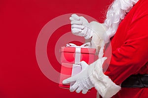 Christmas Photo of Santa Claus gloved hand with red giftbox. no fig
