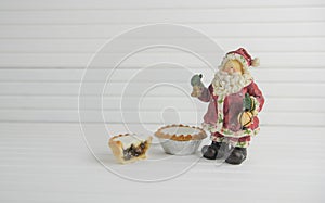 Christmas photography image of christmas food mince pies and toy santa claus with natural white wood background