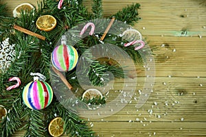 Christmas photography image with green tree branch leaves cinnamon orange slices and colorful bauble decorations and snow