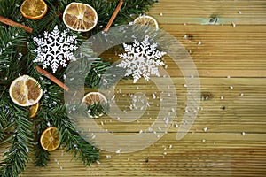 Christmas photography image with green tree branch leaves cinnamon orange slices and white snowflake decorations with snow