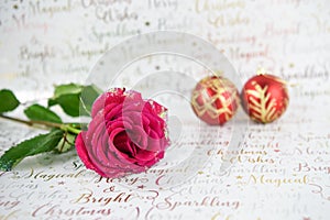 Christmas photography image of red roses with glitter petals and red gold baubles in distance on xmas wrapping paper background