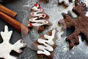 Christmas picture. Chocolate gingerbread Christmas trees and snowflakes sprinkled with flour on a dark background