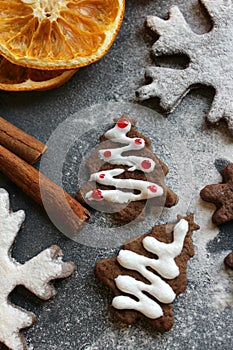 Christmas picture. Chocolate gingerbread Christmas trees and snowflakes sprinkled with flour on a dark background