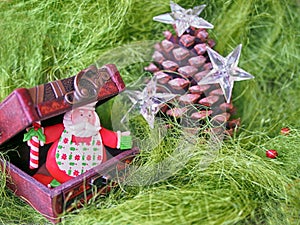 Christmas- pinecone decorated with stars and small wooden chest with funny Santa Claus inside on gr een fluffy background photo