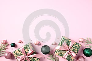 Christmas pink background with stylish vintage gift boxes, fir branches, green baubles. Flat lay, top view. Happy New Year