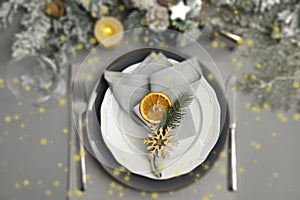 Christmas place setting for festive dinner on grey table, flat lay. Bokeh effect