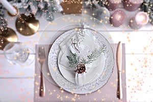 Christmas place setting for festive dinner on white wooden table, flat lay. Bokeh effect