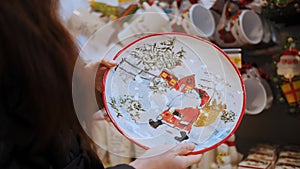 Christmas plate, dish, utensils. present. close-up. Woman looks at Christmas accessories, decor, decorations in a store