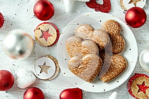 Christmas plate with homemade gingerbreads star baubles on a white table.