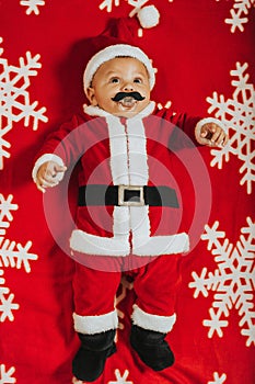 Christmas portrait of adorable newborn baby wearing Santa Claus` outfit