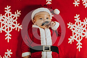 Christmas portrait of adorable newborn baby wearing Santa Claus` outfit