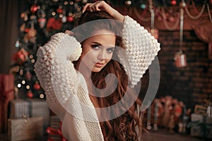 Christmas portrait of attractive woman with knitted sleeves. Beautiful brunette girl with long hair style wears in warm white woo