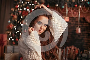 Christmas portrait of attractive woman with knitted sleeves. Beautiful brunette girl with long hair style wears in warm white woo