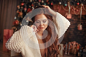 Christmas portrait of attractive woman with knitted sleeves. Beautiful brunette girl with long hair style wears in warm white woo