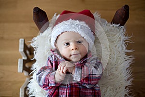 Christmas portrait of cute little newborn baby boy, dressed in c