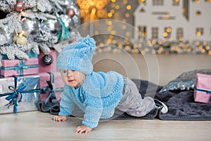 Christmas portrait of cute little newborn baby boy, dressed in christmas clothes and wearing santa hat, studio shot, winter time