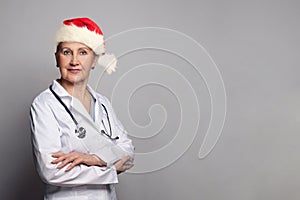 Christmas portrait of doctor or nurse in Santa hat on grey background