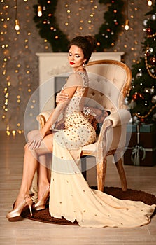 Christmas portrait of elegant woman with wedding hairstyle. Beauty makeup. Beuatiful brunette girl in luxurious dress sitting on