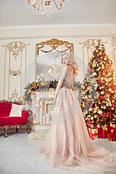 Christmas portrait of a girl in a glittering festive dress on the background of Christmas decor in elegant interior. A woman